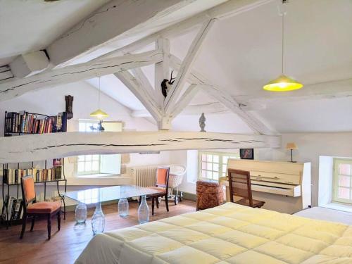 ein Schlafzimmer mit einem Bett, einem Tisch und einem Klavier in der Unterkunft Charmante Demeure 17ème 4ch-3sdb in Bioussac