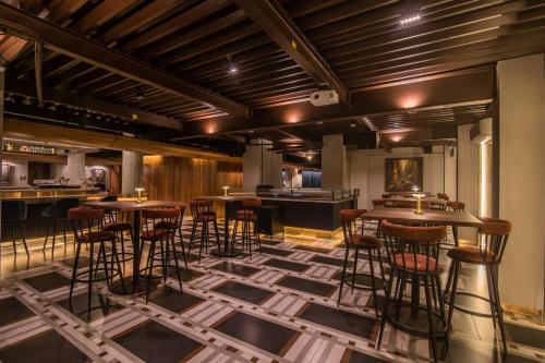 a bar with stools and tables in a room at 37th Crescent Hotel Bengaluru in Bengaluru