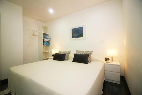 a white bedroom with a large white bed with two pillows at Apartamento Garrano - Casas Barca do Rio by Gerês Casas in Geres