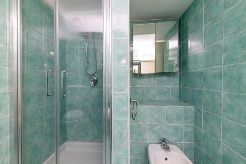 a green tiled bathroom with a shower and a sink at Birago22Capri in Capri