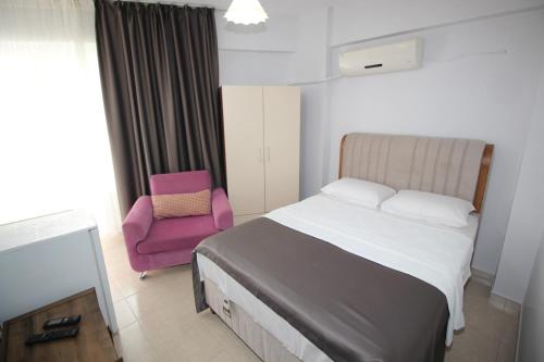 a bedroom with a bed and a pink chair at Pegasus Motel in Avşa Adası