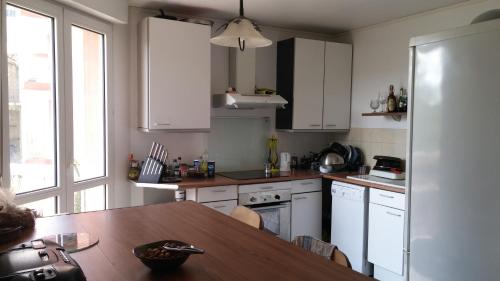 a kitchen with white cabinets and a wooden table at Le Cité Internationale Saint Clair in Caluire-et-Cuire