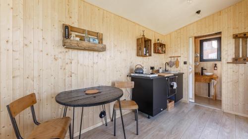 une cuisine avec une table et une petite table avec des chaises dans l'établissement Tiny House haras Normand - 20 minutes d'Étretat, à Annouville-Vilmesnil