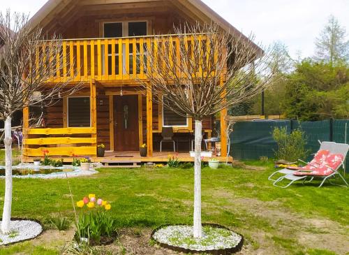 a yellow house with a red chair in a yard at Zagroda Podlas - gospodarstwo agroturystyczne 2 in Aleksandrów