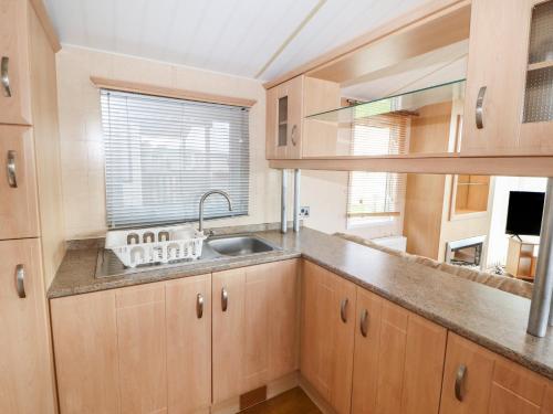 a kitchen with wooden cabinets and a sink and a window at Stanley's Sanctuary in Cockermouth