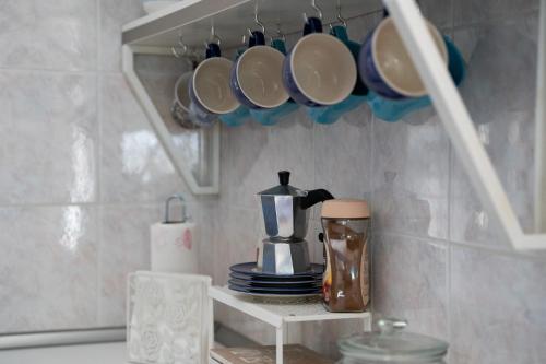 a kitchen counter with cups and a coffee pot on a shelf at Il Nido di Jonathan Livingstone in Rapallo