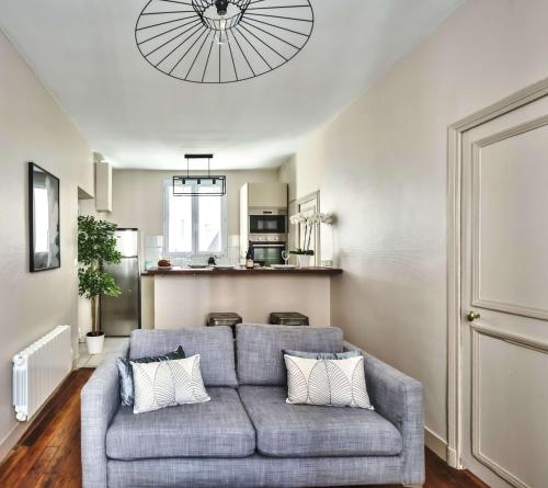 een woonkamer met een grijze bank en een keuken bij 831 - Near South Arena in Paris Olympic Games 2024 in Parijs