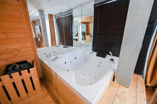 een groot wit bad in een badkamer met een spiegel bij Royal G Max in Golem