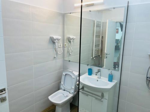 a white bathroom with a toilet and a sink at DXN Luxury Apartment 5 in Năvodari