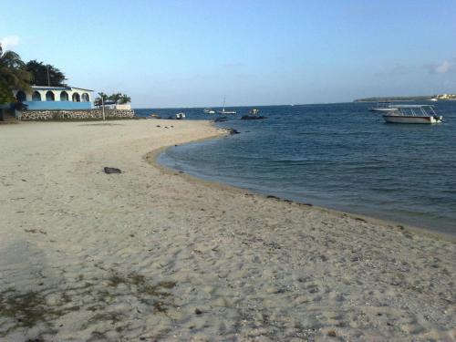 a sandy beach with boats in the water at Paradisia Holidays Mauritius in Trou dʼ Eau Douce