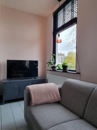 sala de estar con sofá y TV de pantalla plana en Vakantiehuisje De Barones, en Middelburg