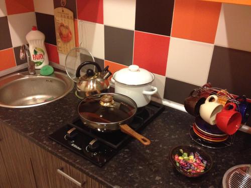 a kitchen counter with a stove with a tea pot and a sink at Добрые апартаменты in Vitebsk