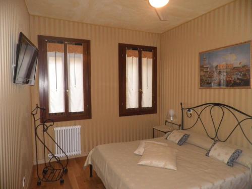 a bedroom with a bed and two windows at Ca' Delle Maschere in Venice