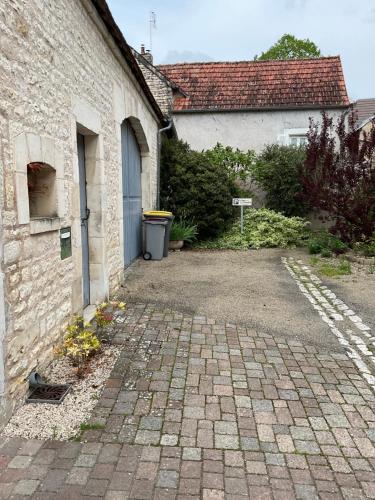 a brick building with a blue door and a driveway at LOGIS DU FAUBOURG petite maison de charme, tranquille, calme et lumineuse in Val-de-Mercy