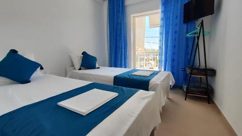 una camera con due letti con tende blu e una finestra di VaspyFlogitaRooms a Flogita