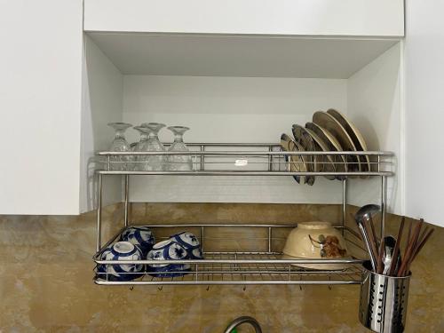 a shelf with plates and vases on it in a kitchen at Thành Vinh Hotel & Apartment in Ho Chi Minh City