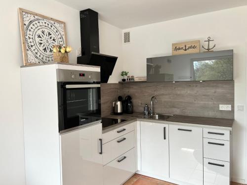 eine weiße Küche mit einer Spüle und einer Mikrowelle in der Unterkunft Ferienwohnung 1 Zimmer App Ankerplatz 43 im Olympiazentrum in Kiel