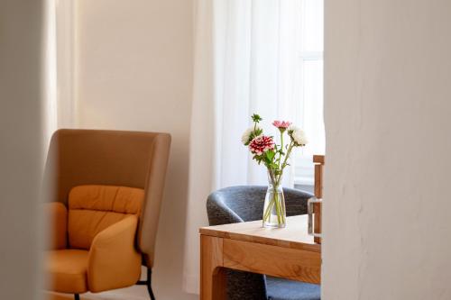 a vase of flowers sitting on a table next to a chair at Pension Goldenes Schiff in Passau