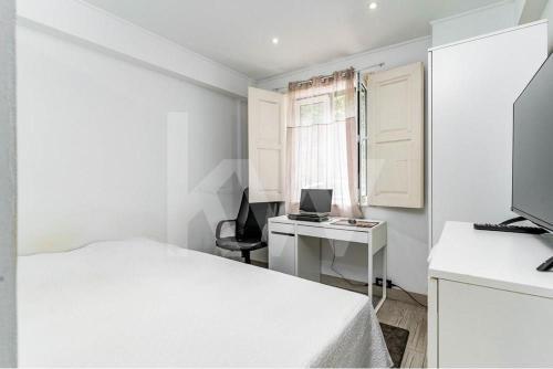 a bedroom with a bed and a desk with a computer at CASA DOS ARCOS in Coimbra