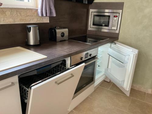 a kitchen with a microwave and a stove top oven at LOGIS DU FAUBOURG petite maison de charme, tranquille, calme et lumineuse in Val-de-Mercy