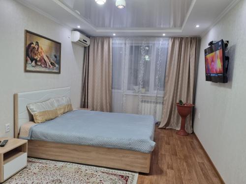 1 dormitorio con 1 cama y TV en la pared en Посуточная квартира на Курмангазы c Wi-Fi en Uralsk
