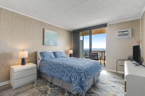 a bedroom with a bed and a television and a balcony at Bayside Beauty in Ocean City