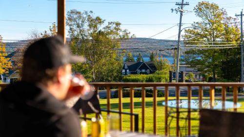 a man sitting on a balcony looking out at a house at Auberge Gisele's Inn in Baddeck