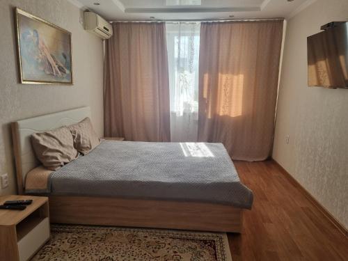 um pequeno quarto com uma cama e uma janela em Посуточная квартира на Курмангазы c Wi-Fi em Oral