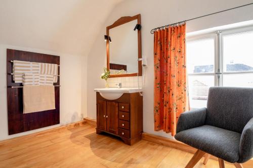 een badkamer met een wastafel, een stoel en een spiegel bij Goldenes Schiff in Passau