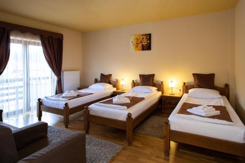 a room with three beds and a couch at Pensiunea Heveder in Praid