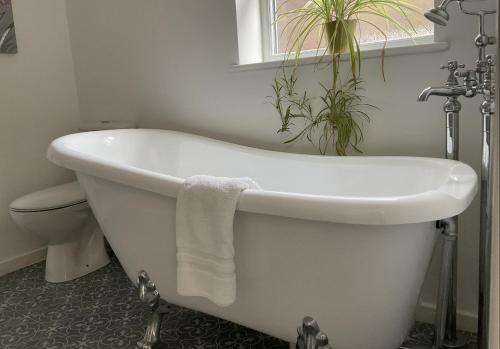 a white bath tub in a bathroom with a plant at The Broomsquire in Tadley
