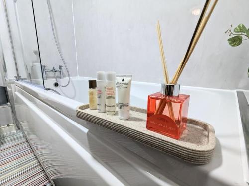 a bathroom with three products on a shelf in a bath tub at City Centre Comfort Northampton in Northampton