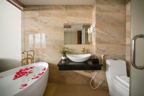 ein Badezimmer mit einer Badewanne, einem Waschbecken und einem Spiegel in der Unterkunft 7 Seven Sea Hotel in Đà Nẵng
