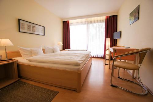 1 dormitorio con cama, escritorio y silla en Pension Winkel, en Braunlage
