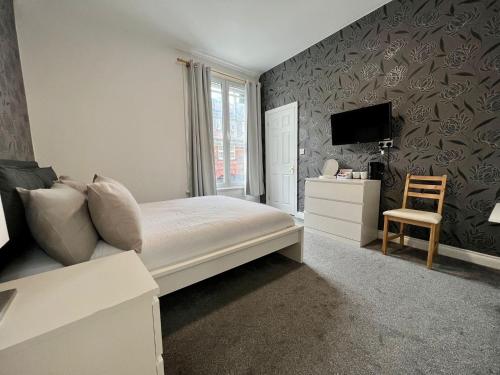 a bedroom with a bed and a tv and a chair at Oxford Street Stays in Southampton