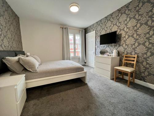 a bedroom with a bed and a tv and a chair at Oxford Street Stays in Southampton