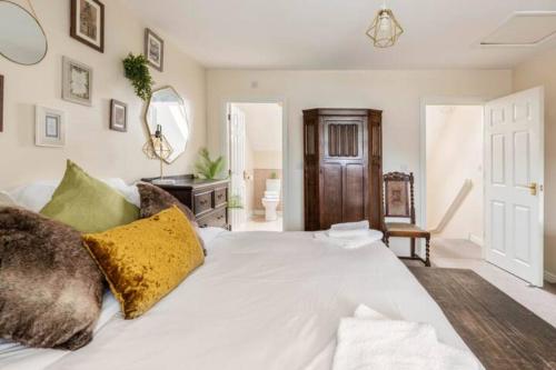um quarto com uma cama branca e almofadas douradas em Lolite Homes - 4 Bed Perfect for NEC Genting Arena Resort World & Airport - Serviced Hawk Home em Birmingham
