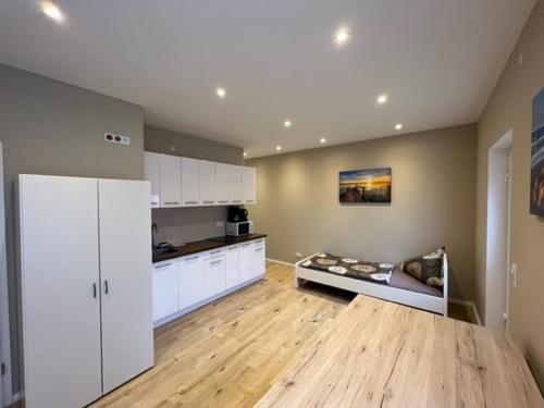 a large kitchen with white cabinets and a wooden floor at Meridian Monteur Apartment in Rodenbach