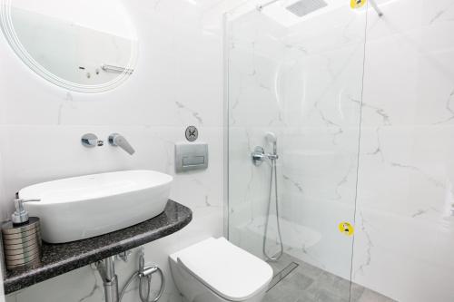 a white bathroom with a sink and a shower at Theodora Apartments in Avia