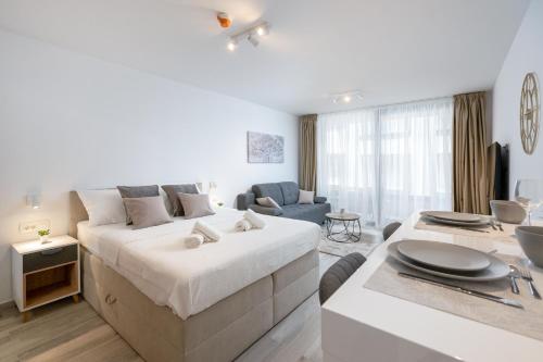 ドゥブロヴニクにあるLuni Apartment in Dubrovnik centerの白いベッドルーム(大型ベッド1台付)、リビングルームが備わります。