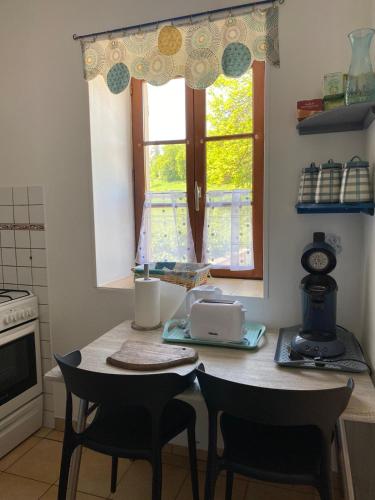 a kitchen with a table and chairs and a window at Petit cocon au cœur du Morvan in Montreuillon