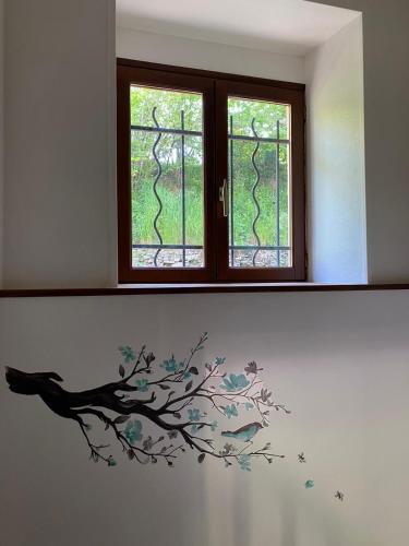 a wall with a tree branch and two windows at Petit cocon au cœur du Morvan in Montreuillon