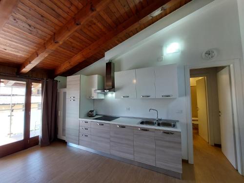 a kitchen with white cabinets and a wooden ceiling at Pizzocolo resort fasano in Gardone Riviera