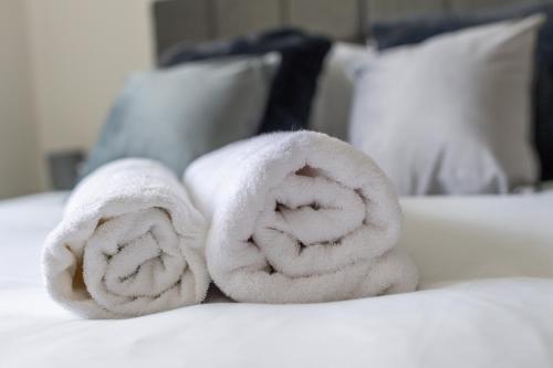 uma pilha de toalhas sentadas em cima de uma cama em Gorgeous Old Trafford apartment em Manchester