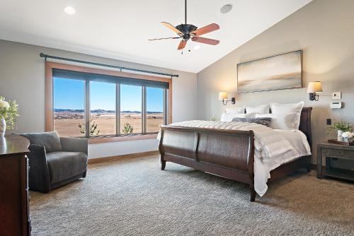um quarto com uma cama, uma cadeira e uma janela em Raz Hideaway 7BR Ranch with Panoramic Mountain Views em Sturgis