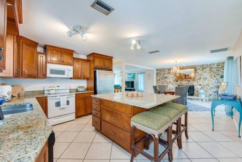 una cocina con armarios de madera y una gran isla con taburetes. en Large pool home and blocks away from the beach, en Daytona Beach