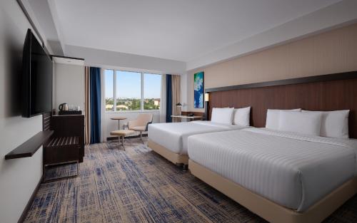a hotel room with two beds and a television at Courtyard by Marriott Tashkent in Tashkent