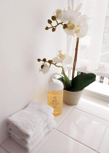 a white bathroom with a towel and flowers on a counter at Dorchester House in Keswick