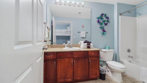 a bathroom with a sink and a toilet and a mirror at Laketown Wharf #1319 by Nautical Properties in Panama City Beach