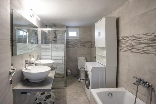 een badkamer met een wastafel, een toilet en een bad bij casa bianca in Nea Kalikratia